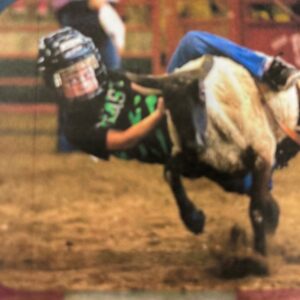 Young boy riding a calf at a rodeo